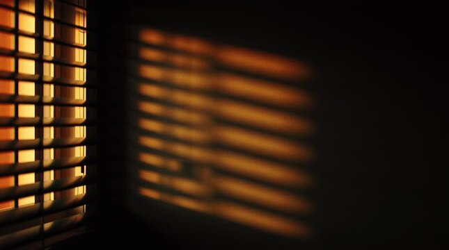 Abstract motion background of sunlight through window blinds, casting high-contrast black and white shadows on a textured surface.

