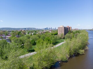 A cyclist enjoys a sunny day on a path in Lasalle, Montreal, Quebec, Canada. The St. Lawrence River flows nearby, with the city skyline in the distance.