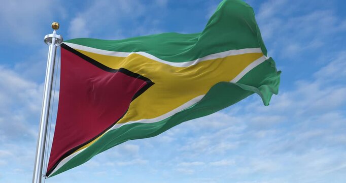 Guyana flag with flagpole waving in wind, rolling clouds background looping, 4K video (Perfect Loop)