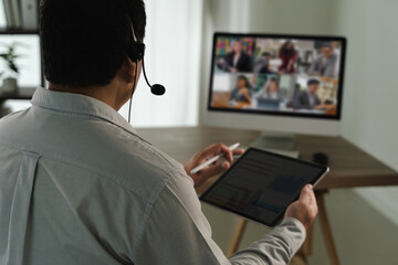 Virtual Meeting and virtual conference person participating virtual meeting using headset, tablet, and computer monitor displaying multiple people