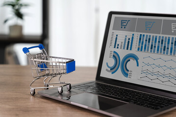 Marketing strategies E commerce dashboard Digital shopping analytics with miniature shopping cart wooden table, showing data charts laptop screen