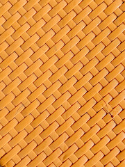Close-up of an orange woven plastic texture in a crisscross pattern, ideal as a seamless background for design, craft, or packaging purposes.