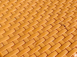 Close-up of an orange woven plastic texture in a crisscross pattern, ideal as a seamless background...