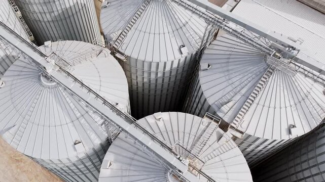 Aerial rotation over shiny silver silos at Dobele grain, flour processing site