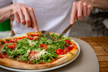 Fresh Italian pizza with arugula, cherry tomatoes, prosciutto and parmesan served at outdoor cafe