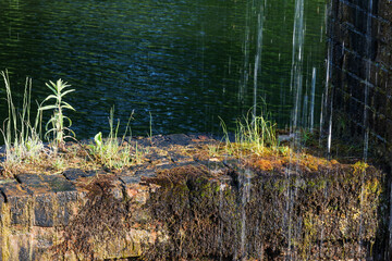 Detail of a stone wall with a small waterfall in the background