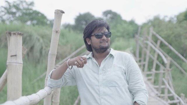 A man stands on the bamboo bridge built over the Damodar River and enjoys the natural beauty.
