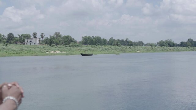 A man stands on the bamboo bridge built over the Damodar River and enjoys the natural beauty.