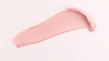 A smooth swipe of pale pink cosmetic cream or lotion is shown on a white background for texture and beauty product advertisement.