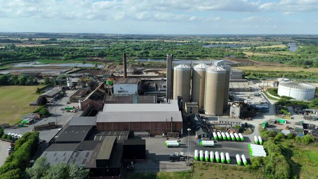 Aerial drone shot sugar production factory rural landscape with storage silos and smoke stacks cooling towers near Newark England UK
