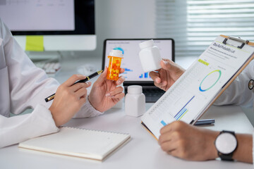 The doctor is holding a bottle of pills and a pen
