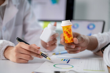 Two people are holding a bottle of medicine and a pen
