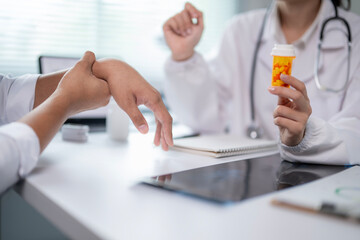 A doctor is holding a bottle of pills and talking to a patient