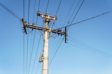 Low angle view of power post and power lines under a blue sky. Auckland.