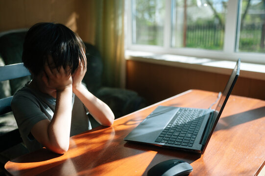 Boy frustrated with distance learning at home using a laptop