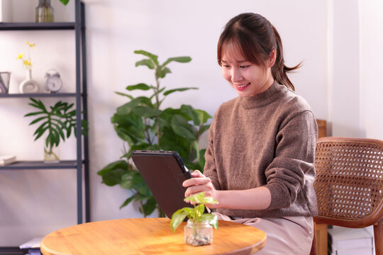 Asian young adult woman engages with tablet for daily artificial intelligence integration at home showcasing smart technology lifestyle