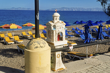 Sunny and peaceful beach on the island of Rhodes, Greece. The sand is golden and dotted with yellow...