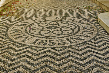 Decorative mosaic of finely arranged pebbles with a central motif decorated with symmetrical...