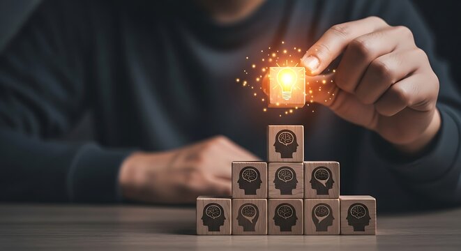 Conceptual thinker placing a radiant light bulb block atop wooden blocks etched with cognitive profiles against a dusky