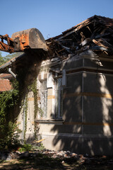 Heavy duty excavator demolishing an old house. Detail on the shingle roof demolish.
