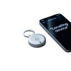 Modern silver tracking device with a keychain ring next to a smartphone displaying locating device text isolated on transparent background