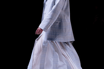 Woman wearing tweed jacket and white skirt, classic fashion clothing on black background