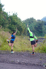 Asian Indonesian couple stretching before trail run, outdoor exercise and sustainable lifestyles