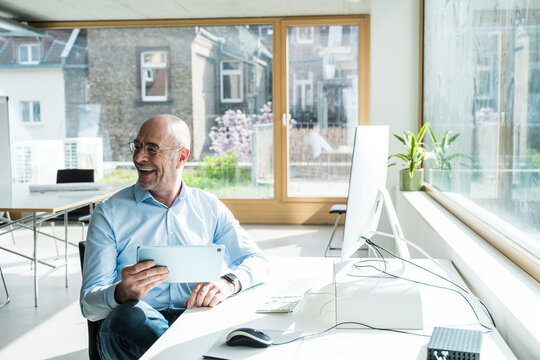 Manager in a modern office holding a tablet and smiling