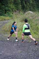 Asian Indonesian couple stretching before trail run, outdoor exercise and sustainable lifestyles