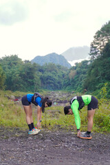 Asian Indonesian couple stretching before trail run, outdoor exercise and sustainable lifestyles