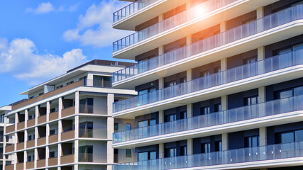 Exterior of a high modern multi-story apartment building - facade, windows and balconies. Modern glass balcony railings.