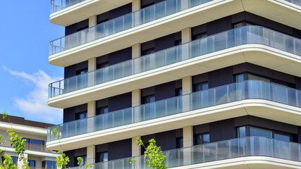 Exterior of a high modern multi-story apartment building - facade, windows and balconies. Modern glass balcony railings.