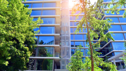 Sustainable glass office building with trees for reducing carbon dioxide. Eco-friendly building in...