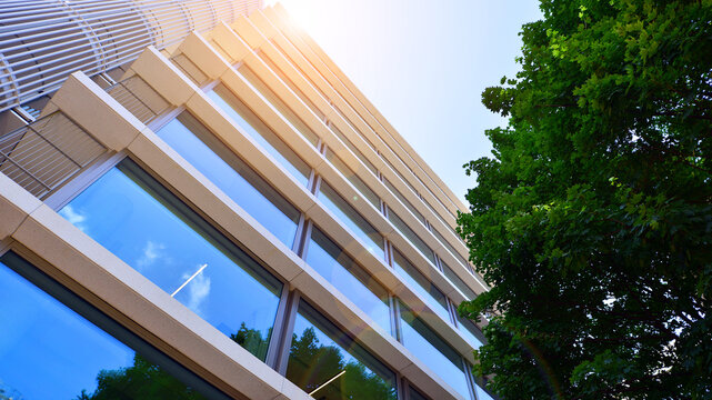 Sustainable glass office building with trees for reducing carbon dioxide. Eco-friendly building in modern city. Office with green environment. Corporate building reduce CO2.