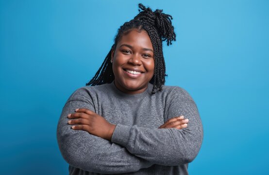 Happy African american plus size woman with braids wearing casual sweater over blue background. Smiling looking camera with crossed arms. Positive person. Confident woman.