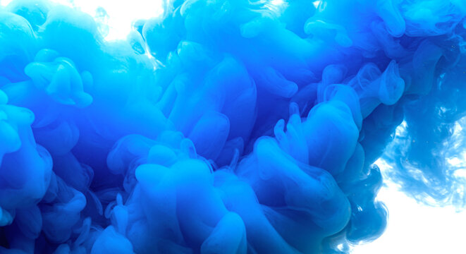A close up view of blue ink swirling and mixing in water creating an abstract cloud effect look