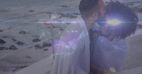 Couple sharing kiss in grey shawl on seaside pier as cosmic overlay receding for travel marketing - Powered by Adobe