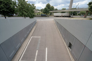 Urban underpass leading to a busy street with trucks and trees during daylight hours