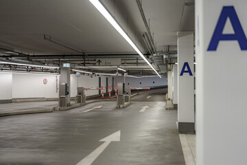 Parking garage interior with directional signs, barriers, and clear exit paths for vehicles at night