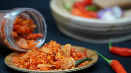 Vibrant close-up of Indonesian sambal with red chilies and crispy garlic on a wooden plate, perfect for culinary, cultural, or food-themed designs.