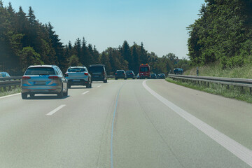 Traffic flows smoothly on a warm sunny day along a highway bordered by trees