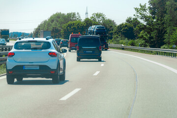 Fototapeta premium Vehicles traveling on a busy highway under bright sunlight with trees lining the road