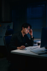 Focused businessman working late at night and concentrating on tasks in a dark office