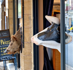Dummy heads of a wild boar and a cow in front of a shop entrance in Les Eyzies, France