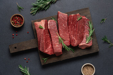 Raw marbled black angus beef sliced ​​on cutting board. Cooking meat dark background top view