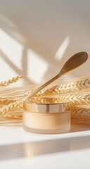 Golden cream jar with wooden spoon, wheat stalks, soft shadows