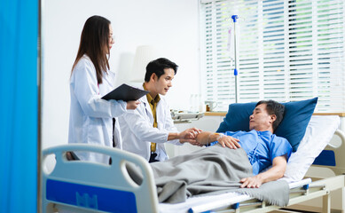 Doctor and nurse warmly support senior patient in hospital bed, discussing diagnosis & care plan.