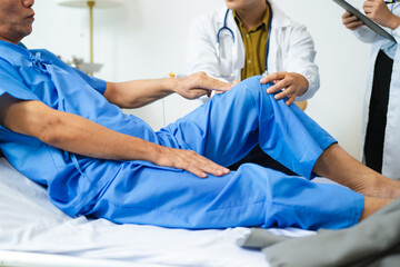 Doctors assess senior patient’s knee injury with care and teamwork in hospital.