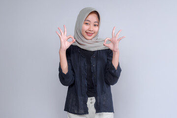 Young Asian woman wearing a hijab, smiling and showing the 