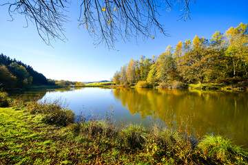 Landscape at the Gerolstein reservoir in autumn. Idyllic nature at the lake in the Eifel region.
